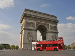 The Arc de Triomphe in Paris with a red double-decker tourist bus in front, symbolizing French immersion and travel.